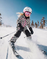 Child wearing the Deux par Deux white and bright pink checkered TEKNIK snowsuit, lifestyle view