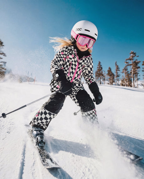 Child wearing the Deux par Deux white and bright pink checkered TEKNIK snowsuit, lifestyle view