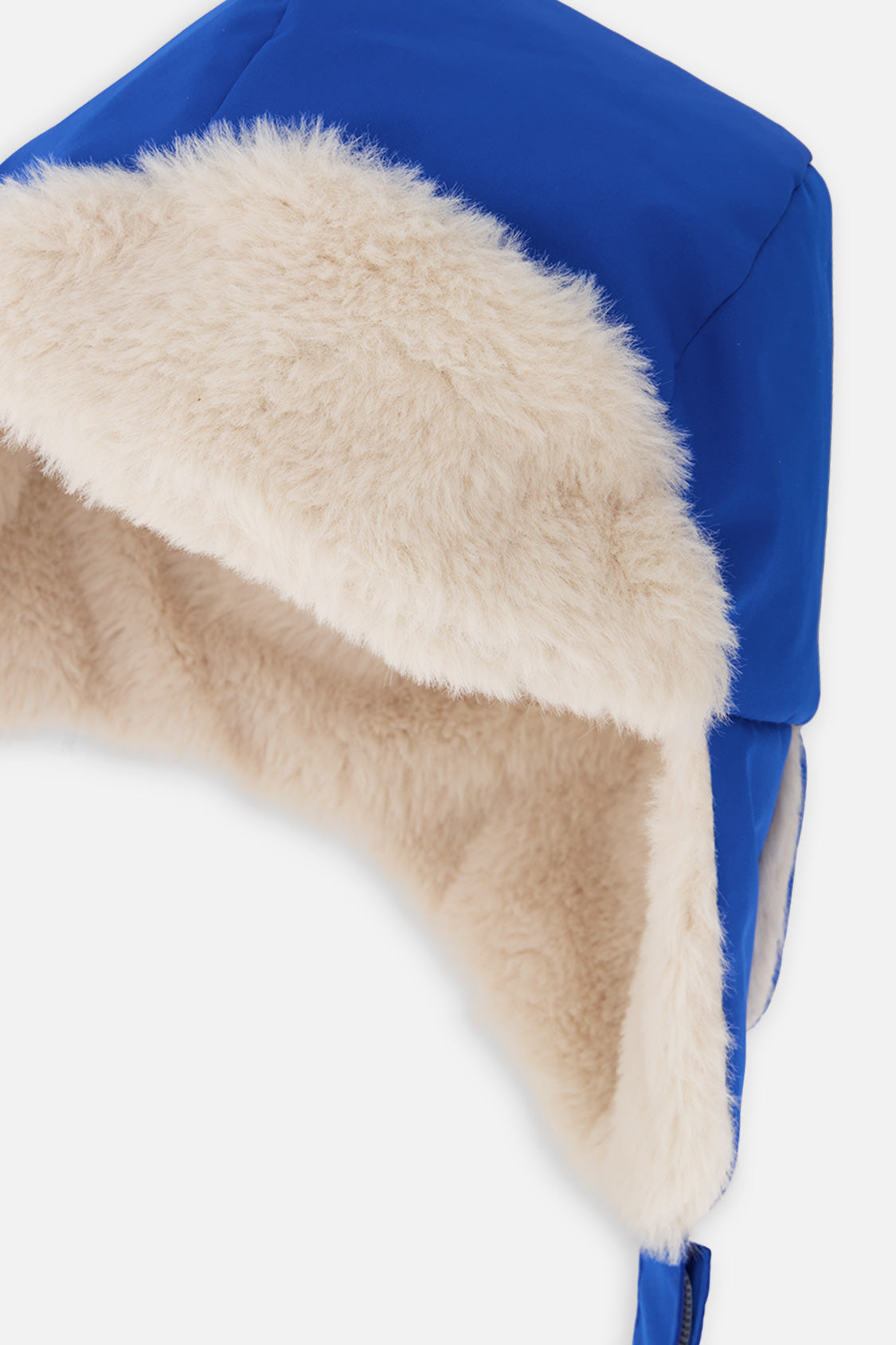 Close-up of the cream plush ear flap and blue polyester shell on the Deux par Deux lined chapka
