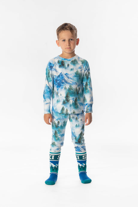 Child wearing the blue mountain print thermal base layer set with ski socks, front view