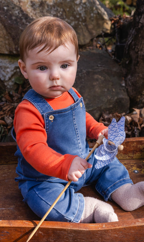 Baby boy sitting outdoors wearing the Deux par Deux light blue denim-look French terry overall