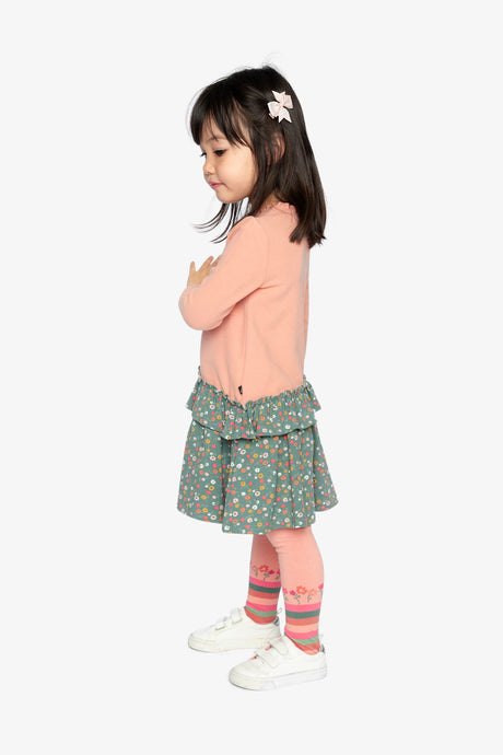 Child looking down in the Deux par Deux pink ribbed dress with a green floral skirt, side view