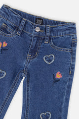 Close-up of the waist button, belt loops and embroidered hearts and flowers on the navy jeans