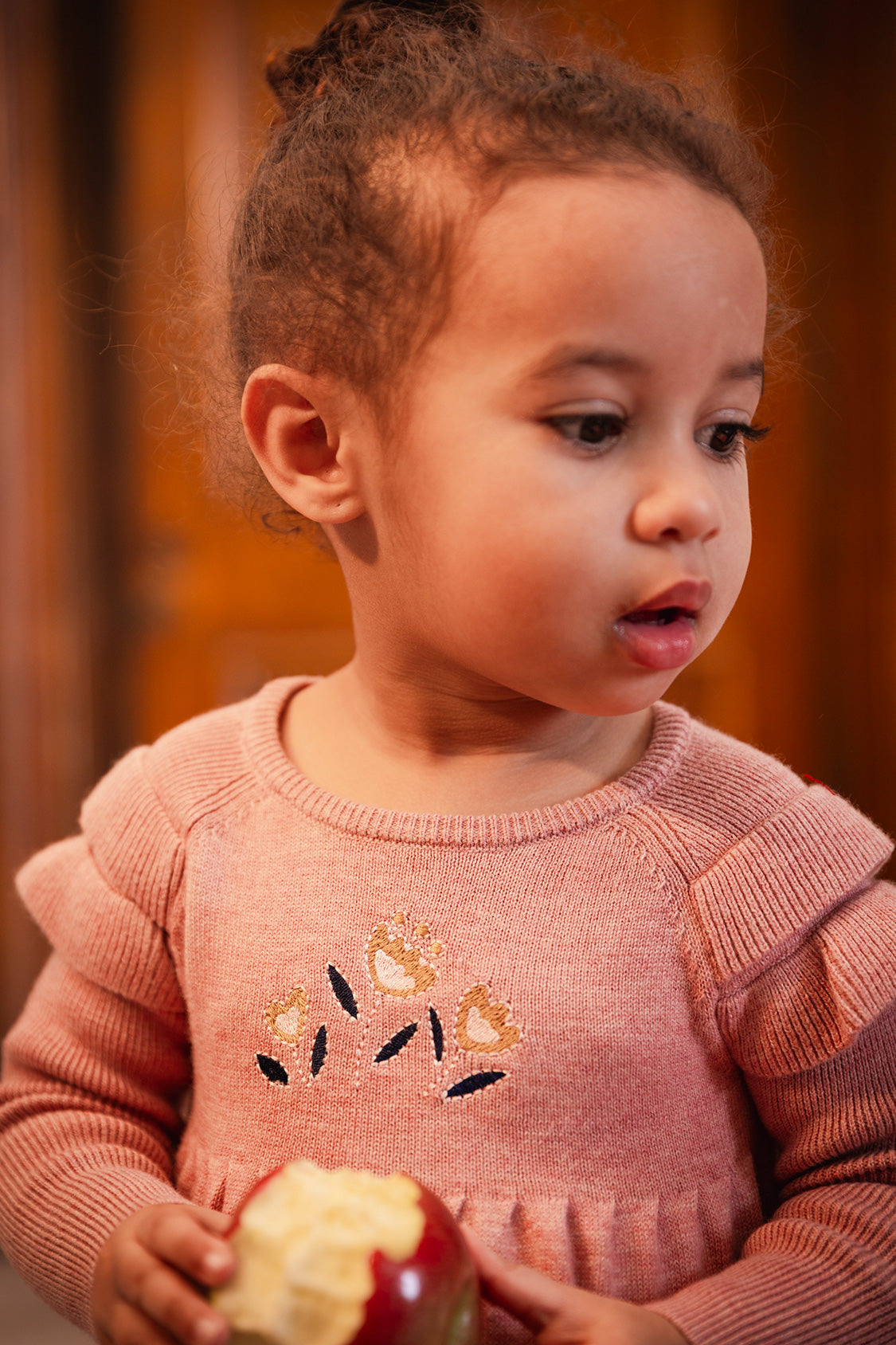 Close-up portrait of a child wearing the pink knit dress with embroidered flowers on the chest