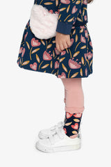 Child wearing the dusty pink tights with a navy tulip skirt, side view with a fluffy heart bag