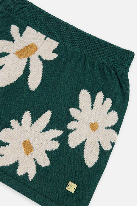 Close-up of the ribbed waistband and oversized daisy jacquard print on the green knitted skirt