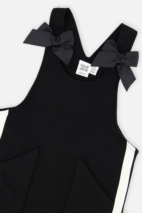 Close-up of the bows on the straps and front patch pockets of the Deux par Deux black jumper dress