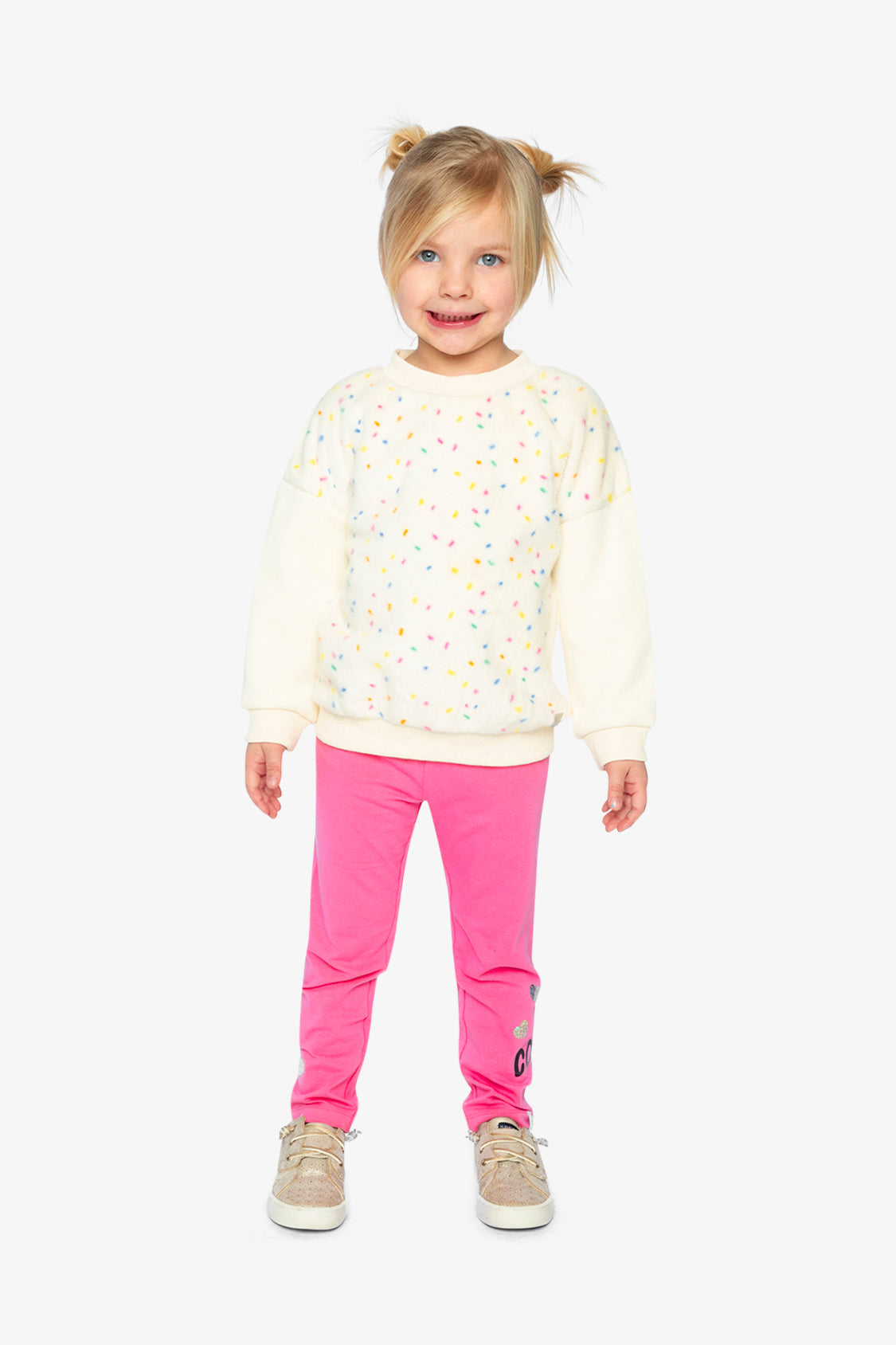 Child in a cream confetti sweatshirt and pink leggings, full-length view