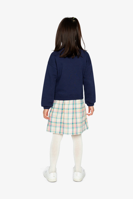 Child wearing the Deux par Deux navy sweatshirt dress with a plaid skirt, back view
