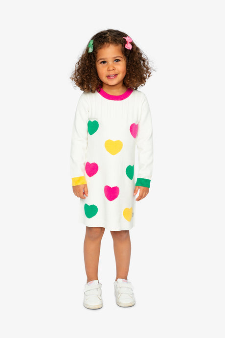 Child wearing the off-white heart knitted dress with a pink ribbed neckline, front view