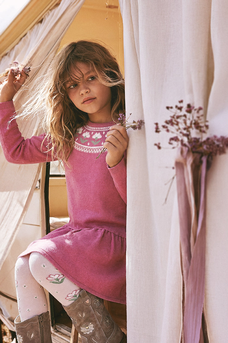 Child holding dried flowers while wearing the raspberry pink flower jacquard dress