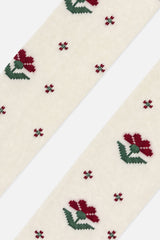 Close-up of burgundy flowers with green leaves on cream knit tights
