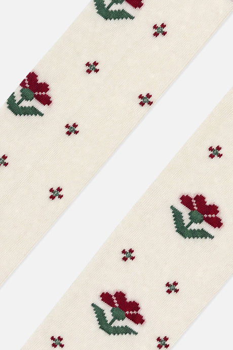 Close-up of burgundy flowers with green leaves on cream knit tights