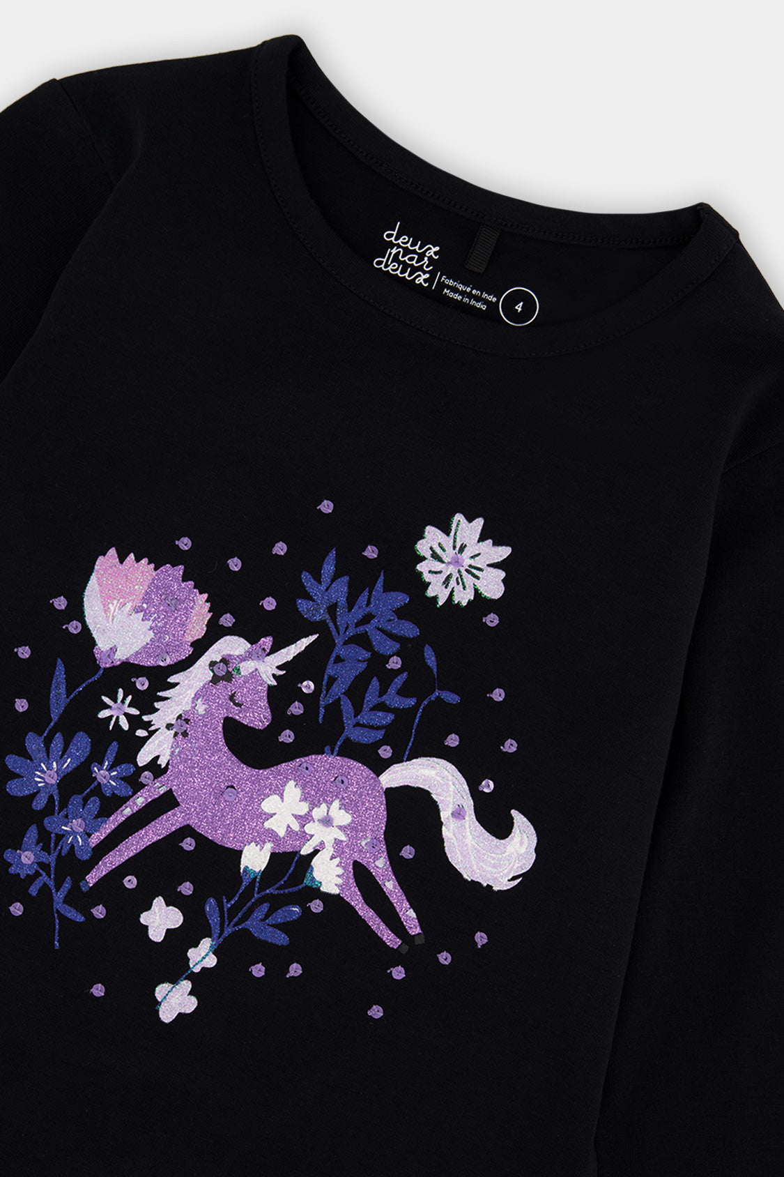 Close-up of the purple glitter unicorn, blue flowers and crew neckline on the black tee