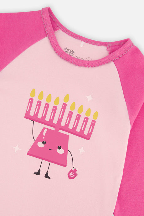 Close-up of the smiling menorah holding a dreidel on the pale pink top beside the hot pink raglan sleeve