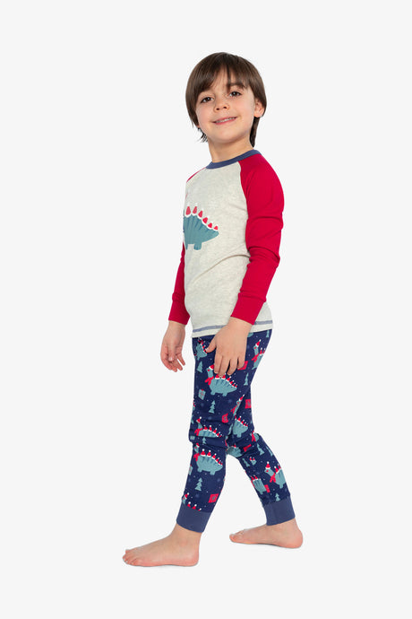 Child wearing the dinosaur pajama set in a side view that shows the red sleeve and navy ankle cuffs