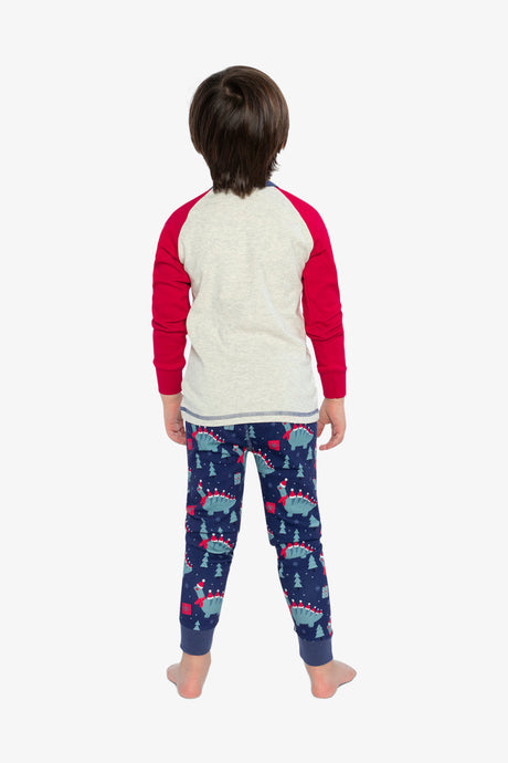 Back view of a child wearing the oatmeal pajama top with red sleeves and the navy dinosaur print pants