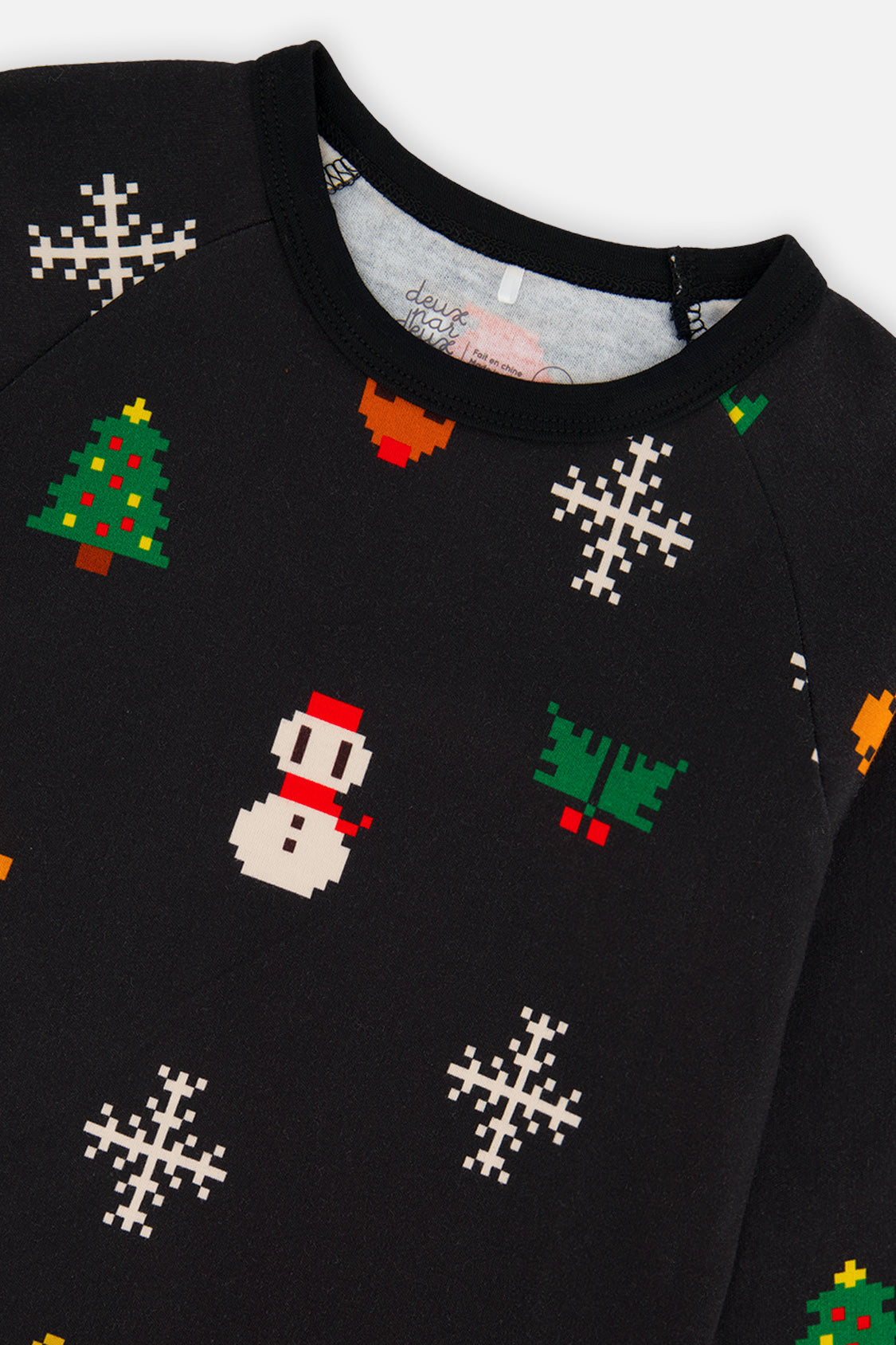 Close-up of the pixel art tree snowman and snowflake print on the black pajama top