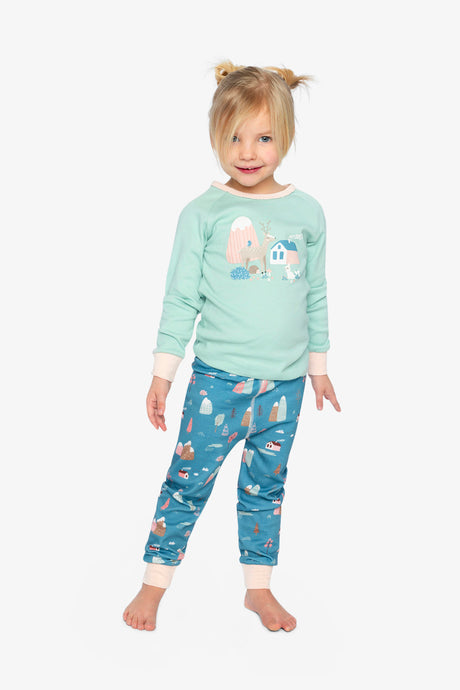 Child wearing the mint and blue house print pajamas with pale pink cuffs, front view