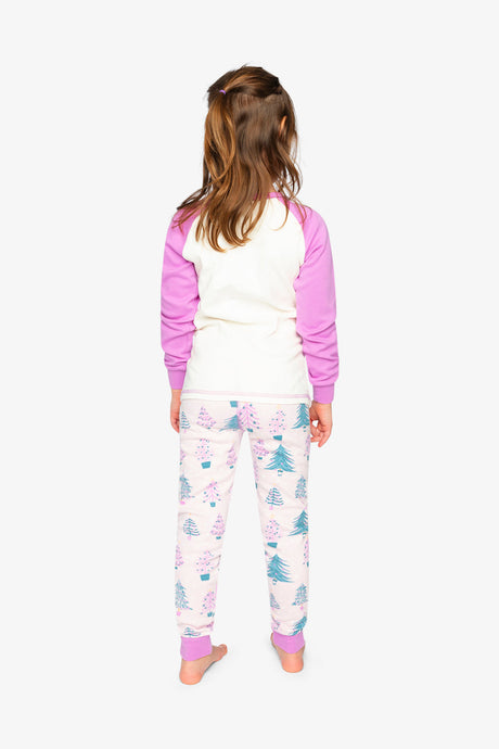 Back view of a child wearing the plain cream pajama top and the pale pink pants printed with decorated trees
