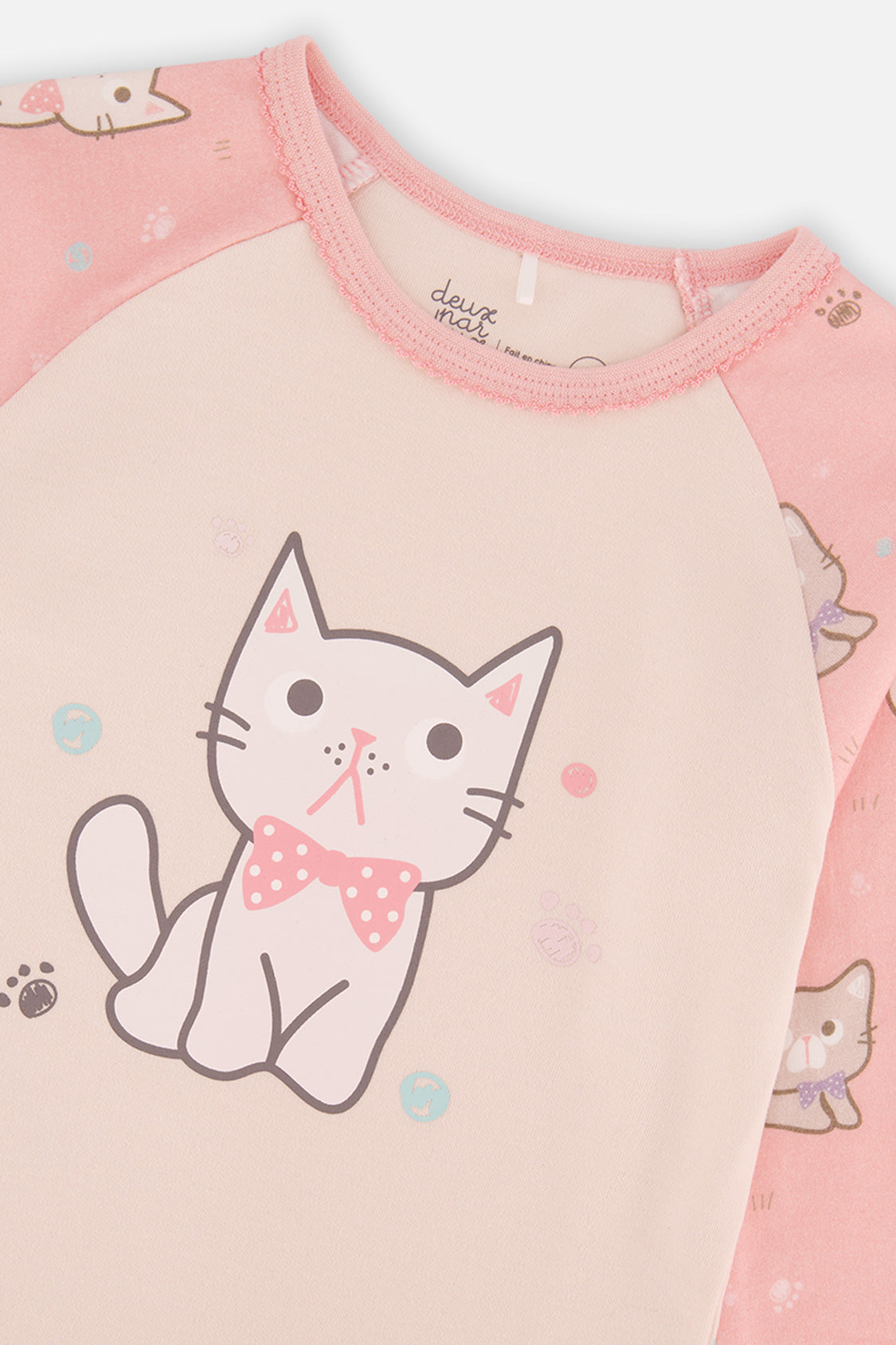 Close-up of the kitten in a polka dot bow on the cream pajama top