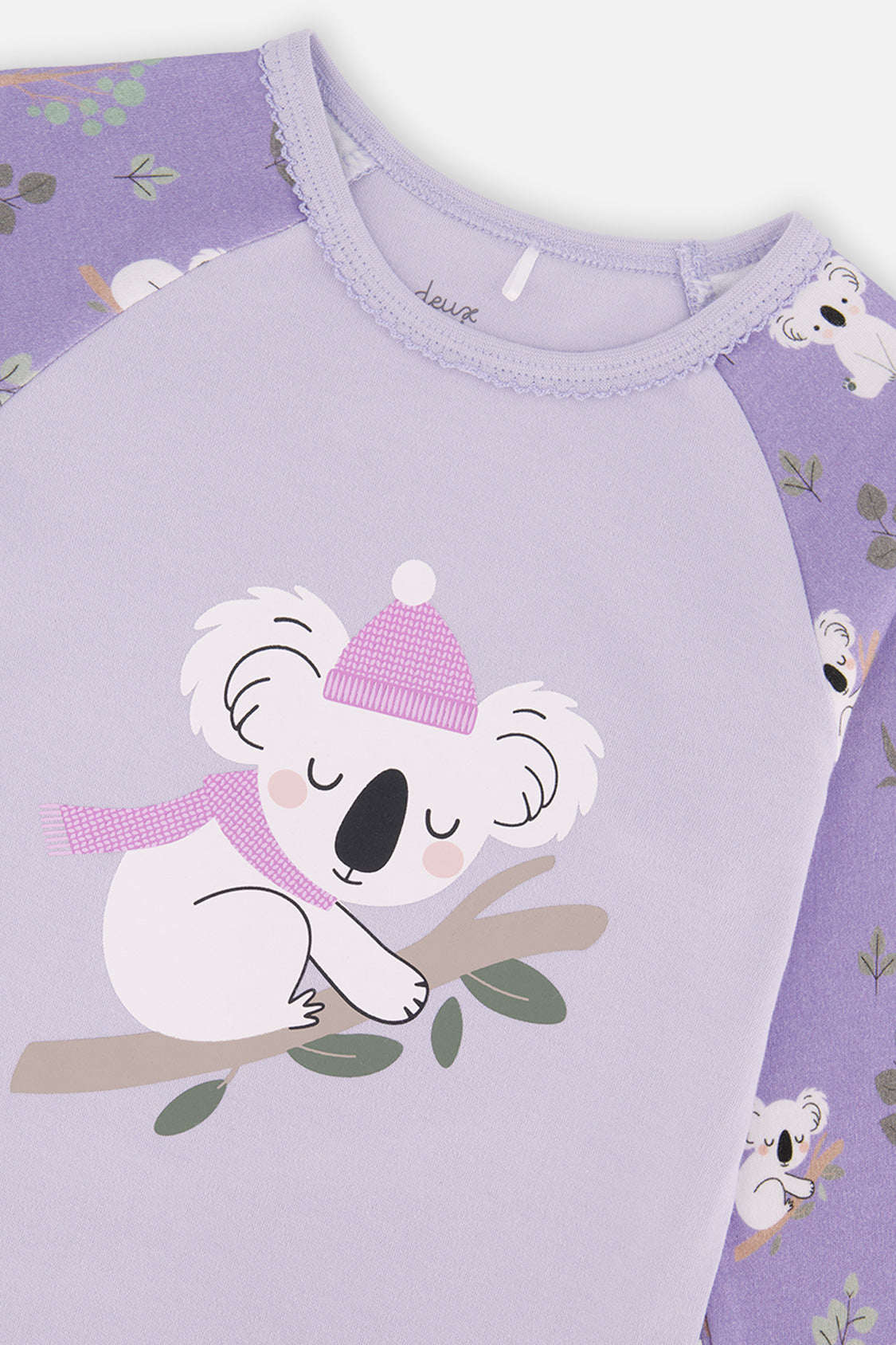 Close-up of the sleeping koala in a pink beanie and scarf on the lilac pajama top with a scalloped neckline