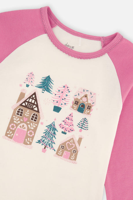Close-up of the gingerbread houses and trees printed on the cream pajama top with a pink scalloped neckline