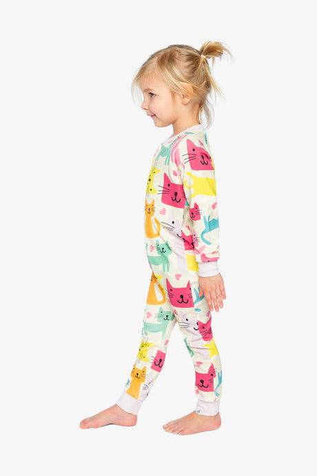 Child wearing the cat print one-piece pajama in a side view with colorful cats along the sleeve