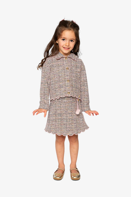 Child wearing the pink and black Deux par Deux cropped jacket with a skirt and gold shoes, full length view