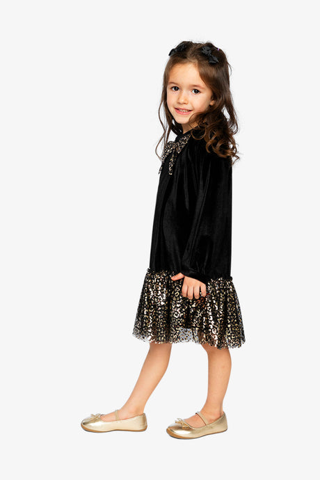 Child wearing the Deux par Deux black velour dress with a gold leopard skirt, side view
