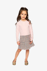 Child wearing the pink and black knit dress with a scalloped skirt hem, front view