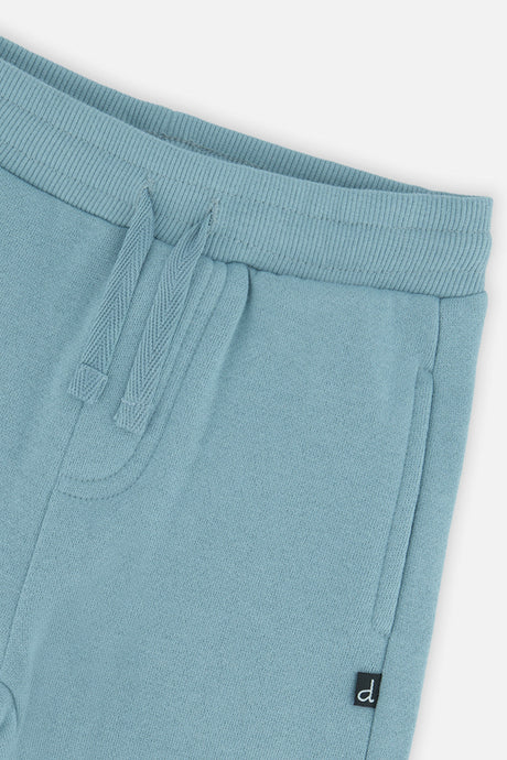 Close-up of the ribbed waistband, drawstring and side pocket on the pale turquoise sweatpants