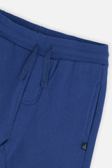 Close-up of the ribbed waistband, drawstring and side pocket on the blue sweatpants