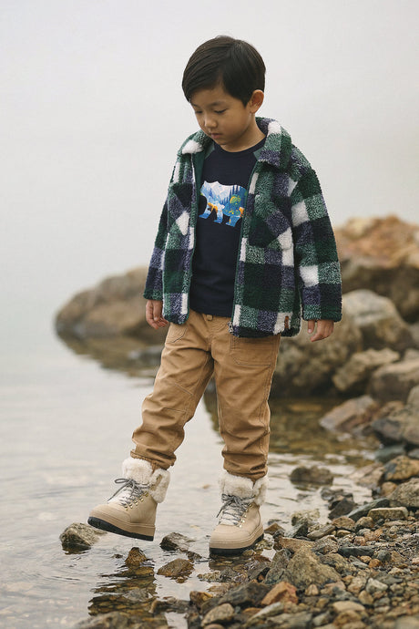 Child standing by rocks and water in the Deux par Deux plaid fleece zipped overshirt