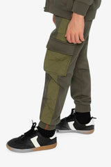 Child wearing the green cargo sweatpants, side view of the flapped cargo pocket and quilted panel