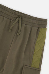 Close-up of the elastic drawstring waistband and quilted side panel on the green cargo sweatpants