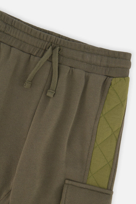 Close-up of the elastic drawstring waistband and quilted side panel on the green cargo sweatpants