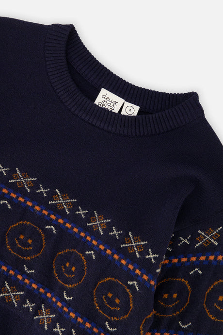 Close-up of the orange smiley faces and cross motifs on the dark blue Deux par Deux sweater