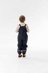 Child wearing the Deux par Deux dark blue rain overalls, back view