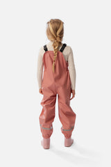 Child wearing the pink Deux par Deux rain overalls with pink rain boots, back view