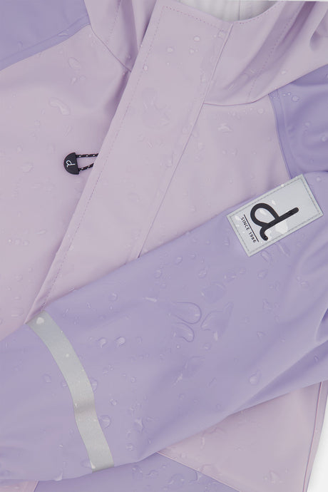 Close-up of the sleeve label, drawcord toggle and reflective sleeve stripe on the mauve Deux par Deux rain jacket