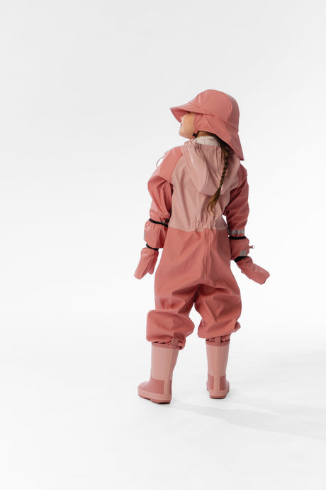 Child wearing the Deux par Deux pink rain one-piece with matching hat and mittens, back view