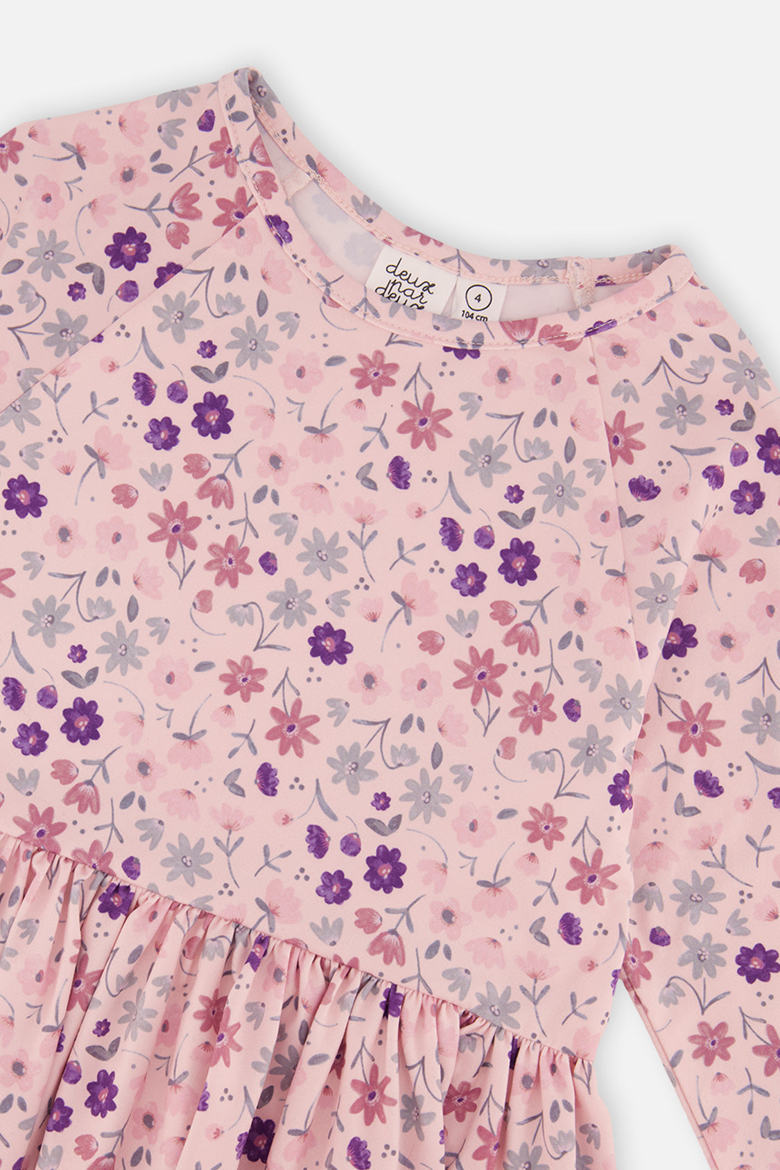 Close-up of the purple flowers, daisies and neckline label on the pink jersey