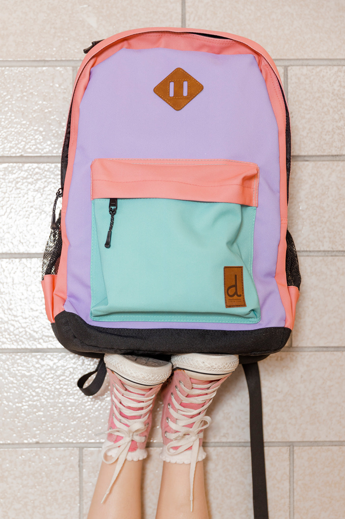 Child wearing the Deux par Deux 21L kids school backpack in Lavender/Turquoise/Orange.