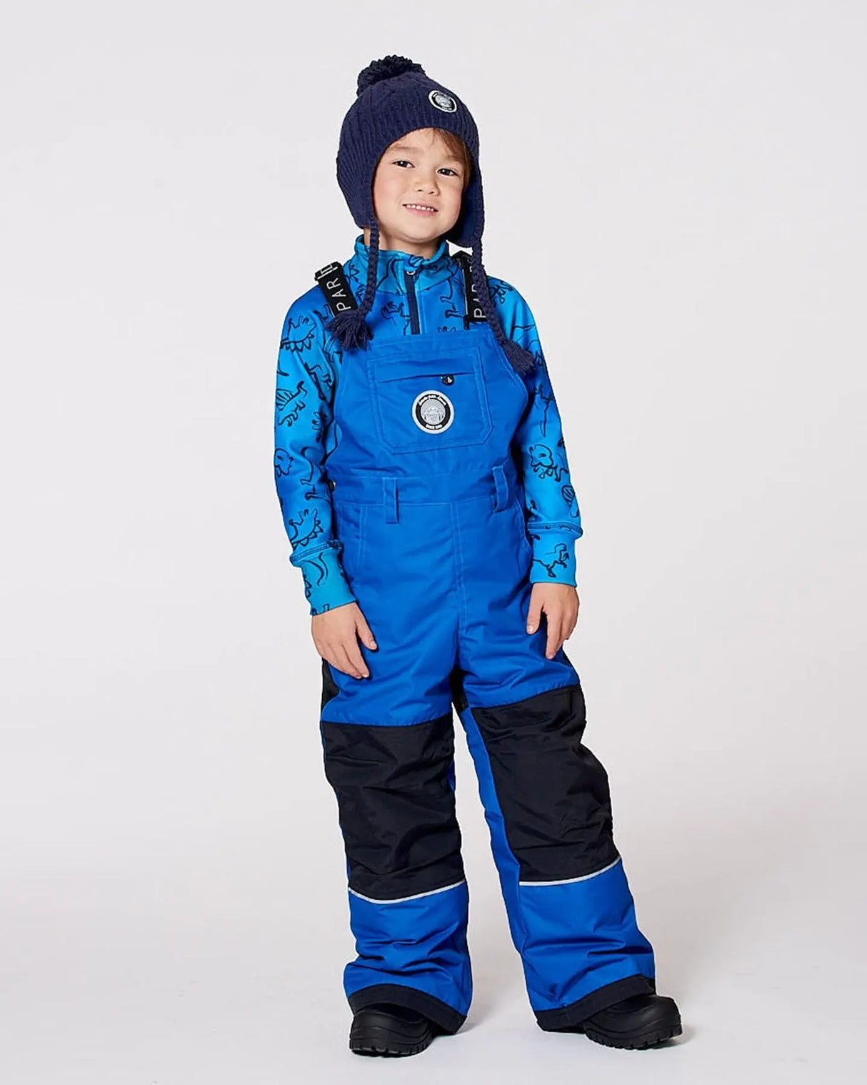 Boy wearing blue insulated snow bib overalls with suspenders.