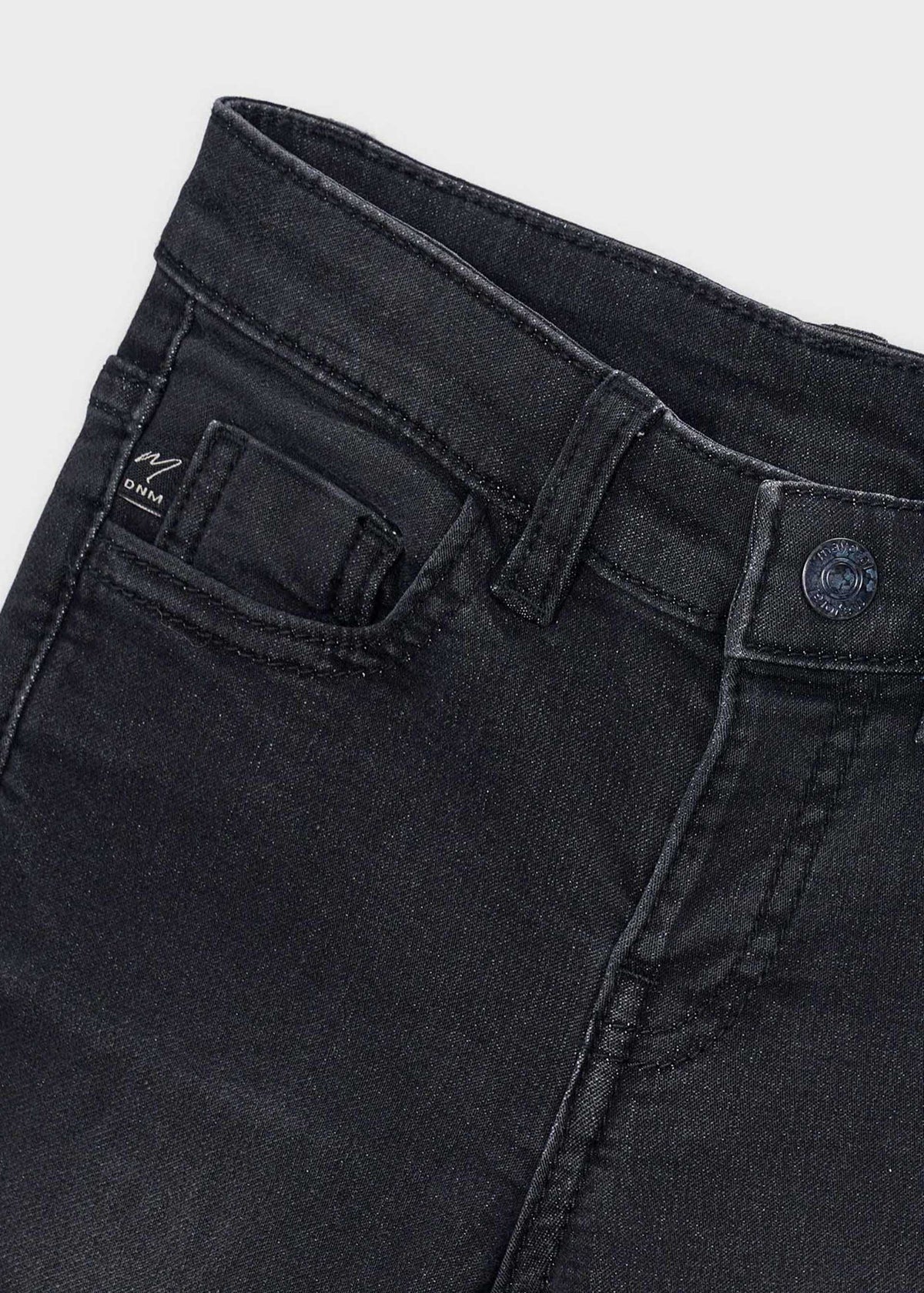 Close-up of the waistband, button and front pocket on the black jeans