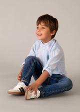 Boy wearing Mayoral Blue regular fit jeans with a white shirt and casual sneakers.
