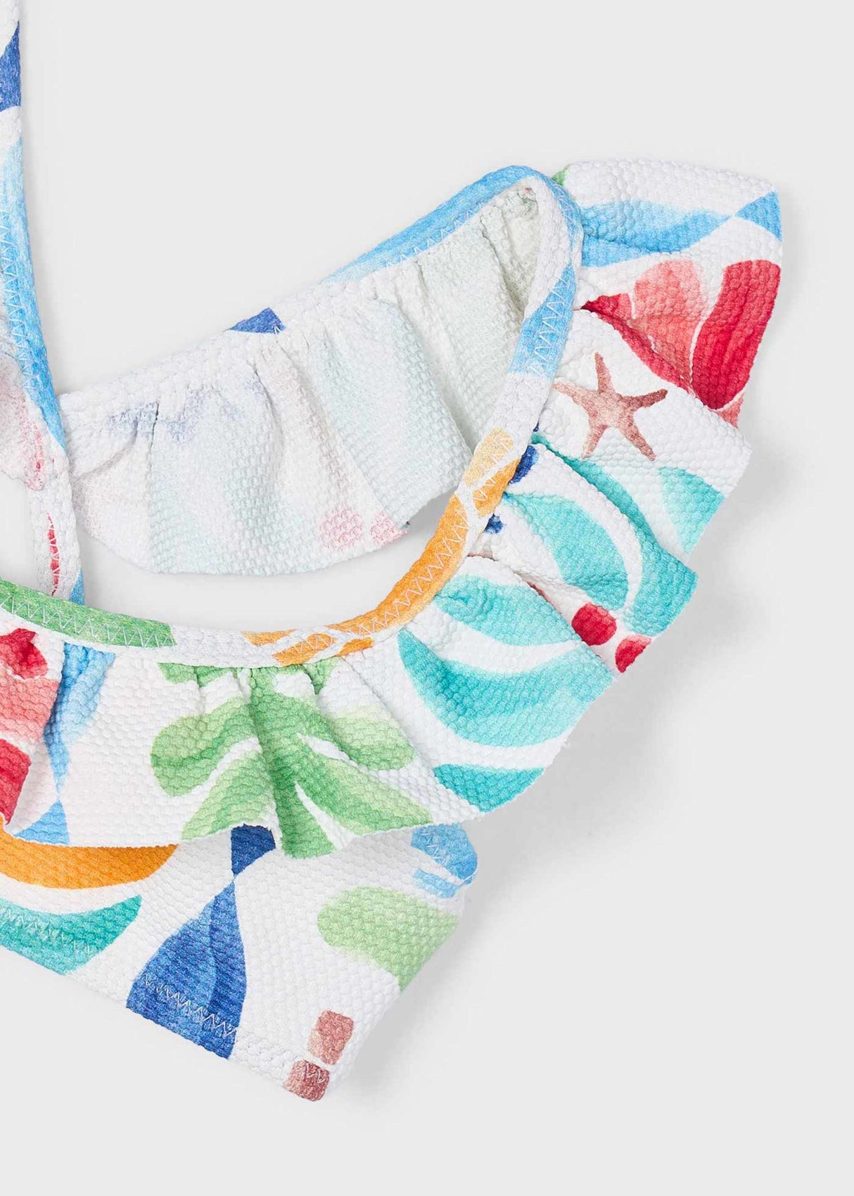 Closeup of Mayoral girls bikini showing ruffle detail, colorful print, and lined swim fabric.