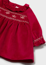 Close-up of the gold-tone embroidered honeycomb smocking and ruffled cuff on the red velvet dress