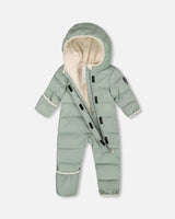 Lifestyle: baby wearing the sage green compressible snowsuit with fleece-lined hood